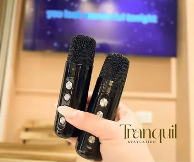 a person holding two microphones in front of a tv at Azure Staycation in Manila