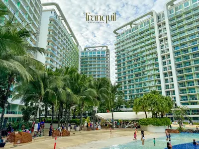 a resort with palm trees and people in a pool at Azure Staycation in Manila