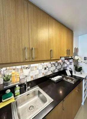 a kitchen with a sink and wooden cabinets at Condo near MOA and NAIA in Manila