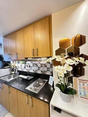 a kitchen with wooden cabinets and a vase of flowers at Condo near MOA and NAIA in Manila