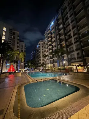 a swimming pool in the middle of a city at night at One Palm Tree Villas Studio w fast WiFi, across from NAIA Terminal 3 in Manila