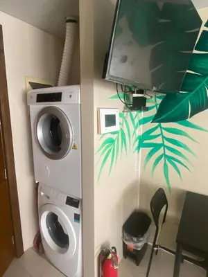 a washing machine and a tv in a room at One Palm Tree Villas Studio w fast WiFi, across from NAIA Terminal 3 in Manila
