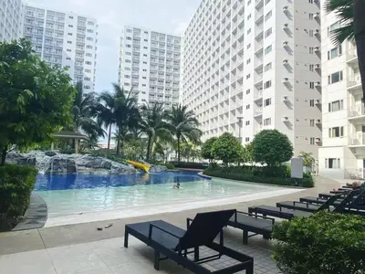 a large swimming pool with benches and buildings at Modern Studio Condo - Shore near MOA- 403B in Manila