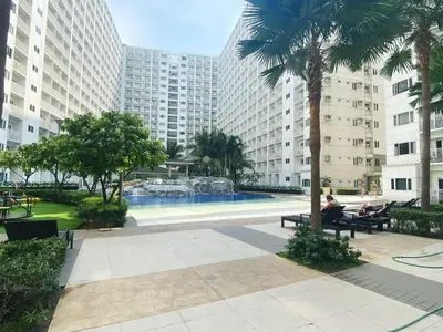 a person sitting on a bench in a park with a fountain at Modern Studio Condo - Shore near MOA- 403B in Manila