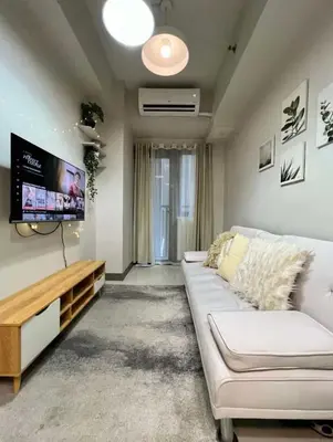 a living room with a white couch and a flat screen tv at S residence, Mall of Asia Area in Manila
