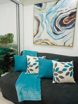 a couch with blue and white pillows and a painting at Maldives Suites, Azure Urban Resorts and Residences in Manila
