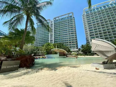 a resort swimming pool with palm trees and buildings at Maldives Suites, Azure Urban Resorts and Residences in Manila