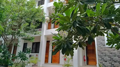 a white building with trees in front of it at The Palines Apartment Hotel near Brittany Palazzo Villar City in Manila