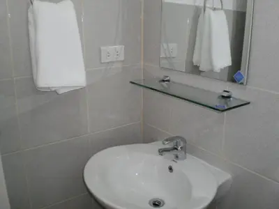 a bathroom with a sink and a mirror at The Palines Apartment Hotel near Brittany Palazzo Villar City in Manila
