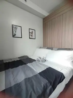 a large bed in a bedroom with two pictures on the wall at Cozy Apartment in Mall of Asia in Manila