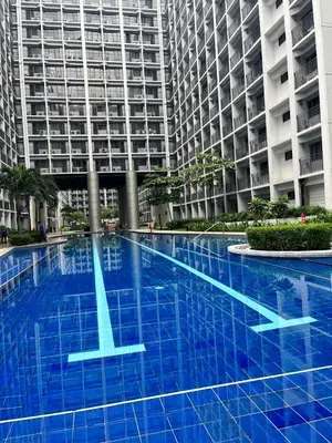 a blue swimming pool in front of a tall building at Cozy Apartment in Mall of Asia in Manila