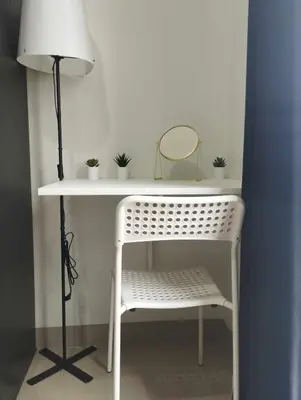 a white desk with a chair and a lamp at Cozy Apartment in Mall of Asia in Manila