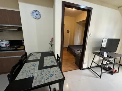 a kitchen and a dining room with a table and a clock at 1 BEDROOM Staycation in Pasay in Manila