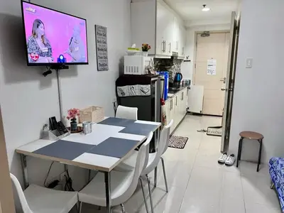 a kitchen with a table and a tv on the wall at Sea Residences Tower E in Manila