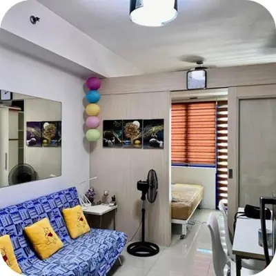 a living room with a blue couch and a bed at Sea Residences Tower E in Manila