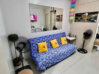 a living room with a blue couch with yellow pillows at Sea Residences Tower E in Manila