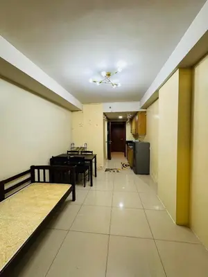 a room with tables and a kitchen with a ceiling at Shell Residences Tower A in Manila
