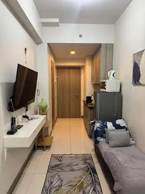 a room with a bed and a desk and a television at Cozy Flat in Pasay City in Manila