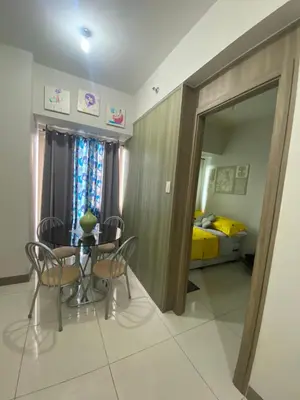 a dining room with a table and chairs and a bedroom at Cozy Flat in Pasay City in Manila