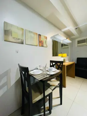a dining table and chairs in a living room at Cozy 1 Bedroom Condo Unit in Manila