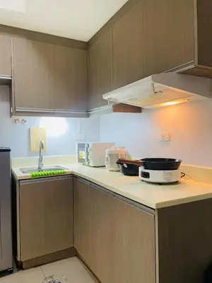 a kitchen with wooden cabinets and a counter top at Cozy 1 Bedroom Condo Unit in Manila