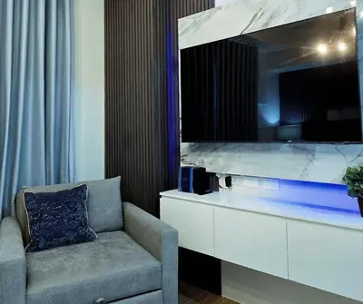 a living room with a chair and a large tv at The Eve Place Staycation PH in Biñan