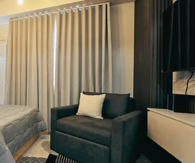 a bedroom with a chair in front of a window at The Eve Place Staycation PH in Biñan