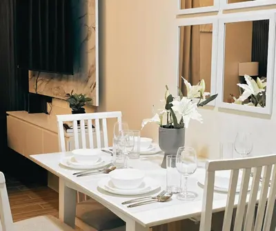 a white dining room table with white plates and glasses at The Eve Place Staycation PH in Biñan