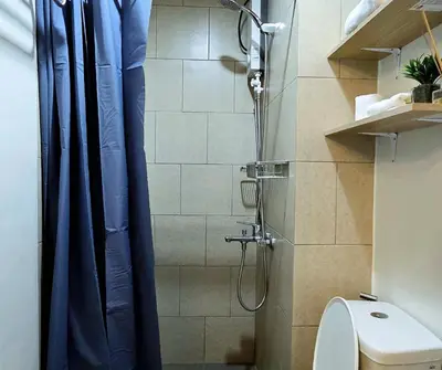 a shower with a blue shower curtain in a bathroom at The Eve Place Staycation PH in Biñan