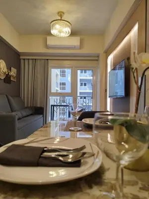 a dining room with a table with a plate and glasses at Savvy Suites Combined 6BR near Okada in Manila