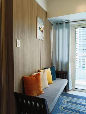 a room with a couch with pillows and a window at Coast Residences in Manila