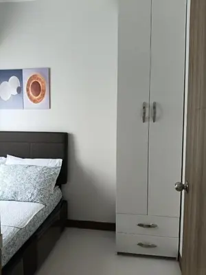 a bedroom with a bed and a white cabinet at Coast Residences in Manila