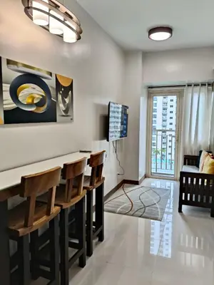 a living room with a bar with chairs at Coast Residences in Manila