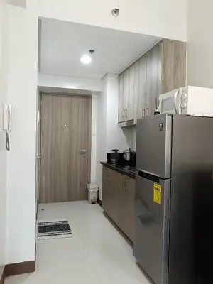 a kitchen with a stainless steel refrigerator and wooden cabinets at Coast Residences in Manila