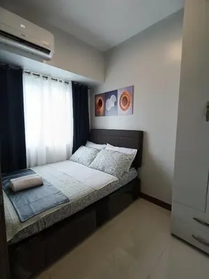 a small bedroom with a bed with a window at Coast Residences in Manila