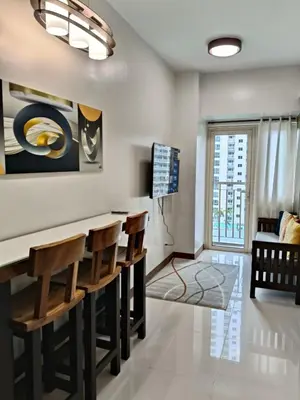 a living room with a bar with chairs at Coast Residences in Manila