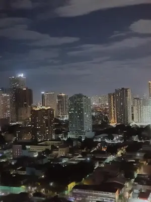 a city skyline at night with tall buildings at Coast Residences in Manila