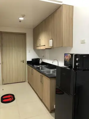 a kitchen with wooden cabinets and a black refrigerator at HY Place Manila in Manila