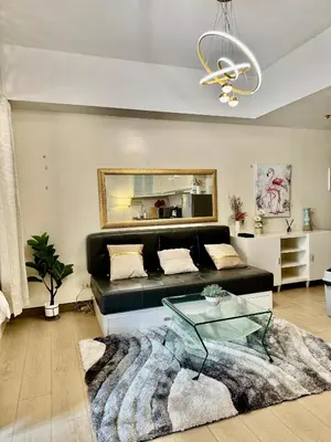 a living room with a black couch and a glass table at Cozy Home at Venice Luxury BGC in Manila