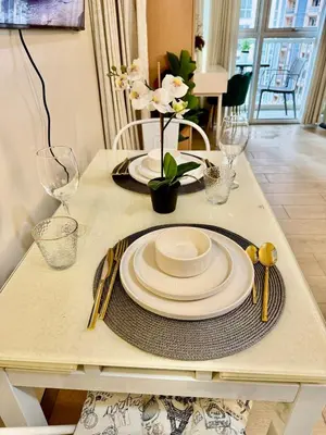 a dining table with plates and glasses on it at Cozy Home at Venice Luxury BGC in Manila