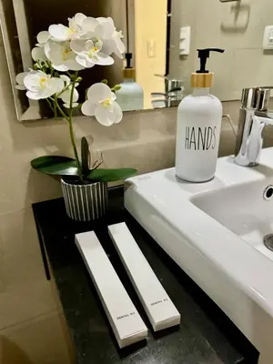 a bathroom sink with a bottle of liquid soap and flowers at Cozy Home at Venice Luxury BGC in Manila