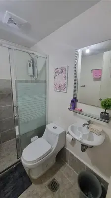 a bathroom with a toilet and a sink and a shower at Joms Cozy Staycation in Calamba