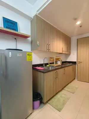 a kitchen with wooden cabinets and a stainless steel refrigerator at Shore Condotel Metro Staycation in Manila
