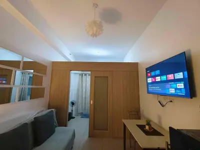a living room with a couch and a flat screen tv at Shore Condotel Metro Staycation in Manila