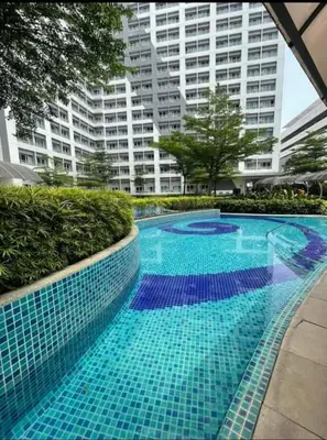 a swimming pool with blue tiles in front of a building at VM Staycation Tower 3 Grace Residence Taguig in Manila