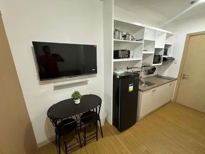 a kitchen with a small table and a television on a wall at VM Staycation Tower 3 Grace Residence Taguig in Manila