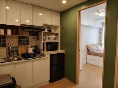 a kitchen with white cabinets and a green wall at Cadence Place 2BR Pasig Condo for upto 6pax with Free Parking in Manila