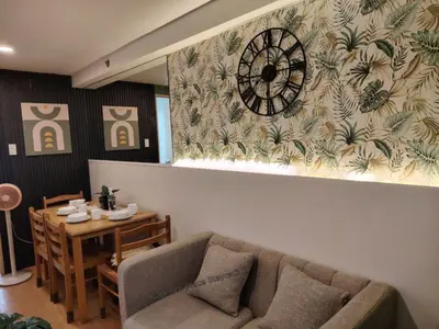 a living room with a couch and a clock on the wall at Cadence Place 2BR Pasig Condo for upto 6pax with Free Parking in Manila