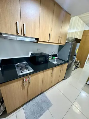 a kitchen with wooden cabinets and a black counter top at Kathys Crib 11th flr at Shell Residence in Manila