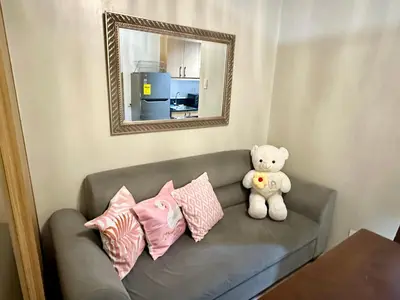 a teddy bear sitting on a couch with pillows at Kathys Crib 11th flr at Shell Residence in Manila